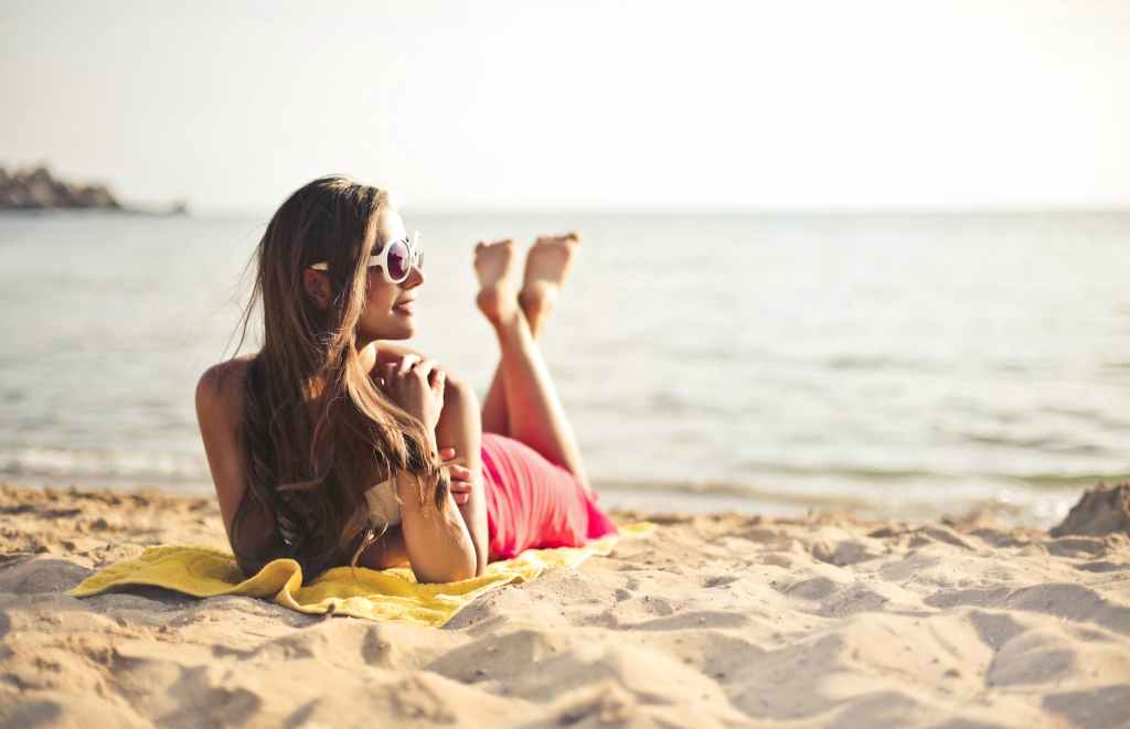 woman smiling while lying on beach sand